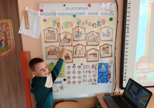 Chłopiec wskazuje palcem na tablicy obrazek z omawianym prawem dzieci.