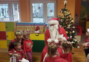 Mikołaj wręcza dzieciom prezenty.