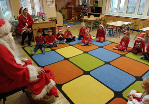 Mikołaj słucha wypowiedzi dzieci siedzących na dywanie.