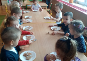 Dzieci z grupy Gwiazdeczki siedzą przy stoliku, czekają na ozdoby do pierników.