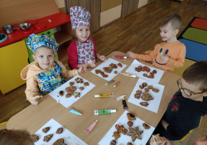 Dzieci ozdabiają cukierniczymi pisakami pierniki