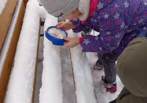 Dziecko ogląda śnieg przez lupę