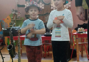 Dziewczynka i chłopiec wykonują ruchy w rytm muzyki.