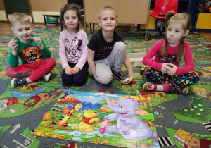 Dzieci układają puzzle z serii „Kubuś Puchatek i przyjaciele”.