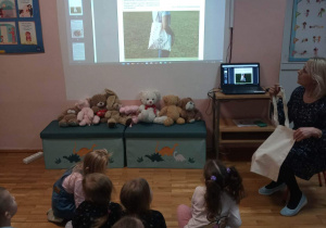 Dzieci wraz z nauczycielką oglądają prezentację multimedialną.