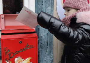 Dziewczynka wrzuca list do skrzynki Św. Mikołaja.