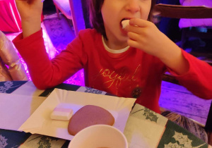 Dziewczynka je pierniki i pije kakao.