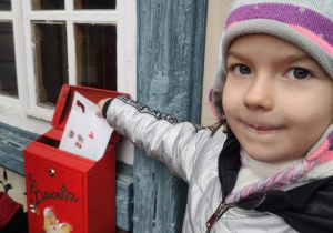 Dziewczynka wrzuca list do skrzynki Św. Mikołaja.