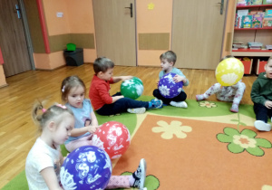 Przedszkolaki oglądają balony- rozpoznają narysowane na nich dinozaury.