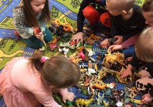 Dzieci segregują figury dinozaurów.