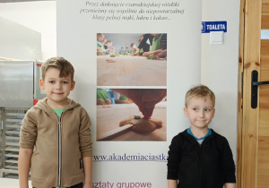 Dwóch chłopców stoi na tle billboardu Akademii Ciastka