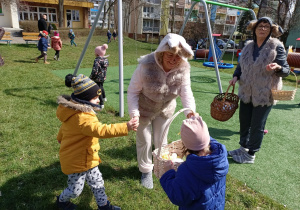 Dzieci wkładają jajka do koszyczków zajączków.