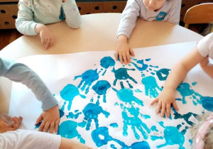 Dzieci z grupy Gwiazdeczki odbijają dłonie pomalowane na niebiesko tworząc serce.