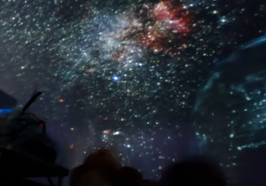 Dzieci obserwują gwieździste niebo w mobilnym planetarium.