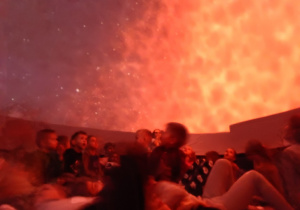 Dzieci w mobilnym planetarium obserwują inne planety