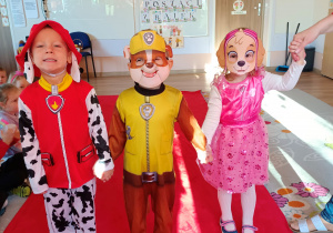 Troje dzieci prezentuje swoje przebrania z bajki "Psi Patrol"