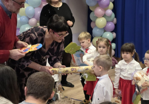 Pani dyrektor pasuje dziecko na przedszkolaka dużym ołówkiem