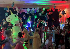 Bal karnawałowy. Dzieci w bajkowych przebraniach tańczą.