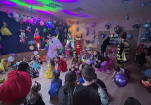 Bal karnawałowy. Dzieci w bajkowych przebraniach tańczą.