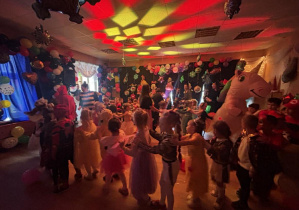 Bal karnawałowy. Dzieci w bajkowych przebraniach tańczą.