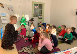 Dzieci z grupy IV słuchają historii o Mikołaju opowiadanej przez prowadzącą.