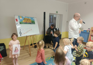 Grupa dzieci patrzy na dziewczynkę trzymającą obrazek