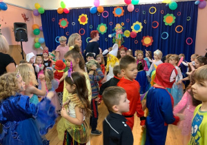 Dzieci przebrane w stroje wraz z personelem przedszkola tańczą w rytm muzyki