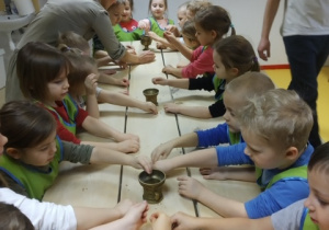 Dzieci dotykają ziarenek pszenicy.