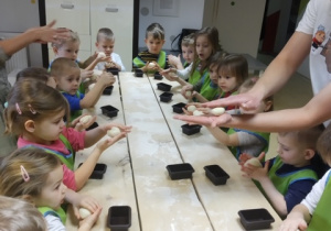 Dzieci wyrabiają i formują ciasto na chleb.