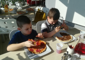 Dwóch chłopców jedzących pizzę