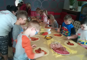 Dzieci smarują swoją pizzę sosem