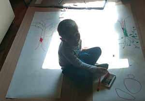 Marcinek rysuje z bratem na dużych kartonach.