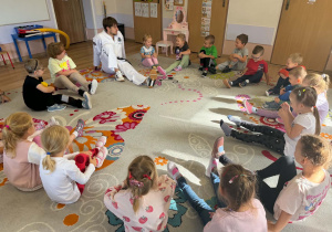 Pan od taekwondo siedzi z dziećmi w kole i pokazuje ćwiczenia